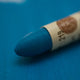 A close-up of a Sennelier oil pastel on a  blue background.