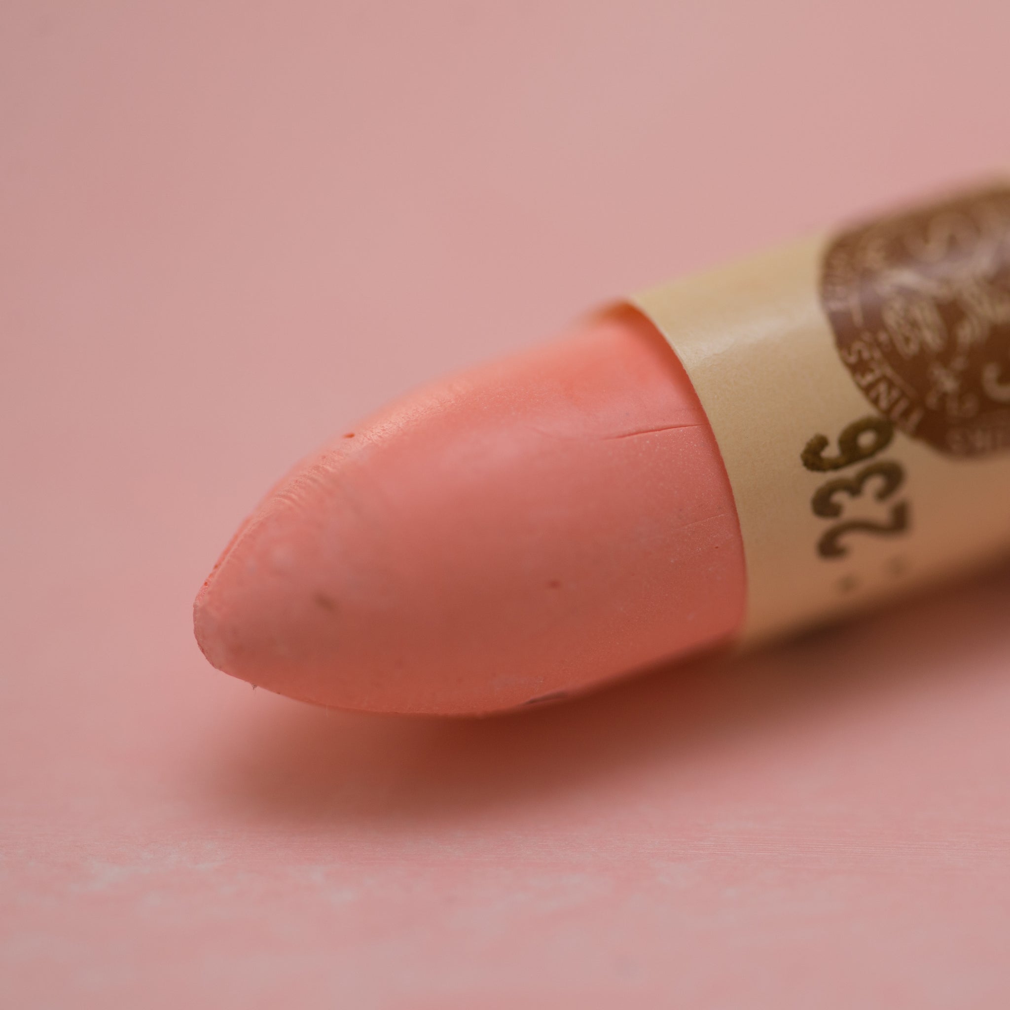 A close-up of a Sennelier oil pastel on a  pink background.