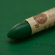 A close-up of a Sennelier oil pastel on a green background.