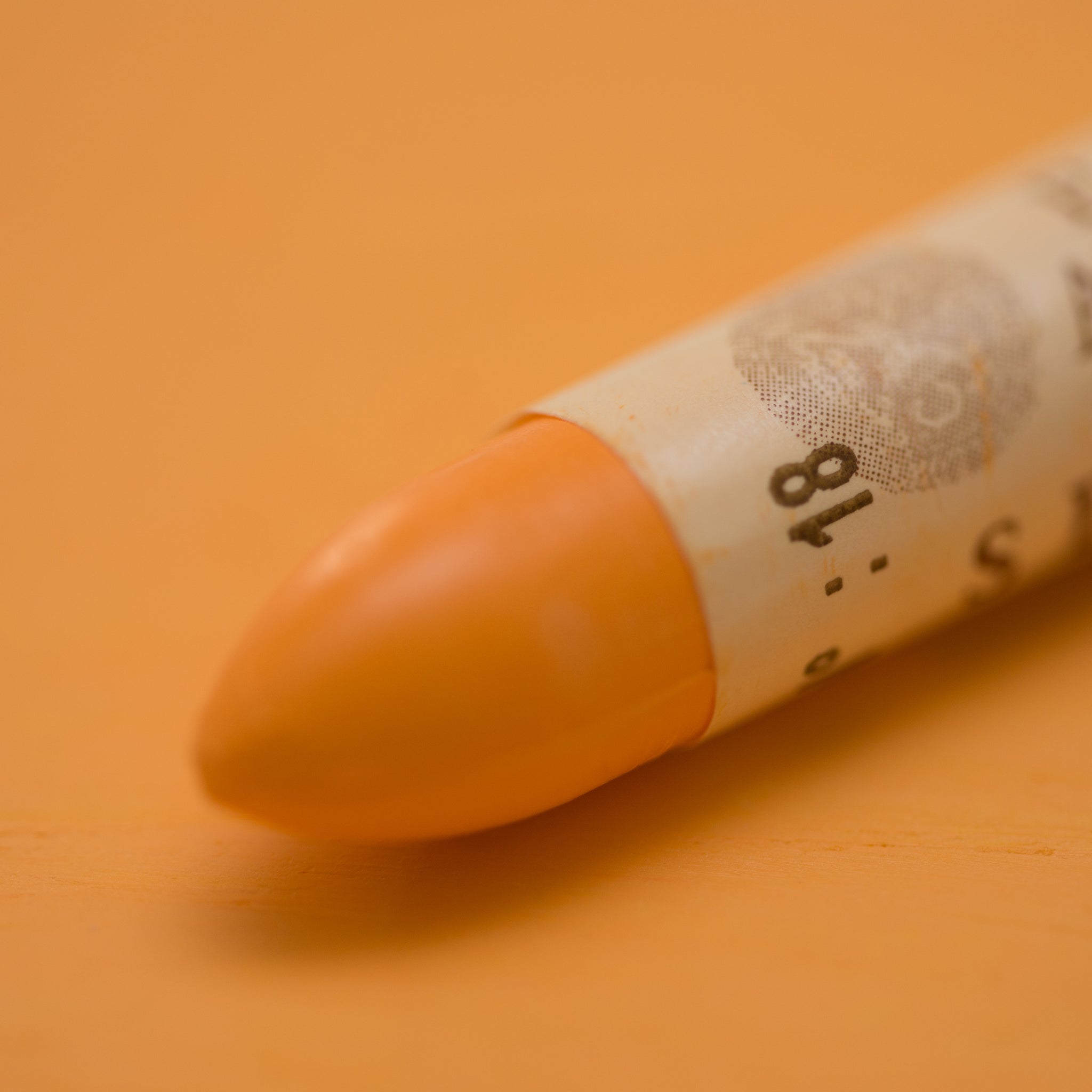 A close-up of a Sennelier oil pastel on a Yellow background.