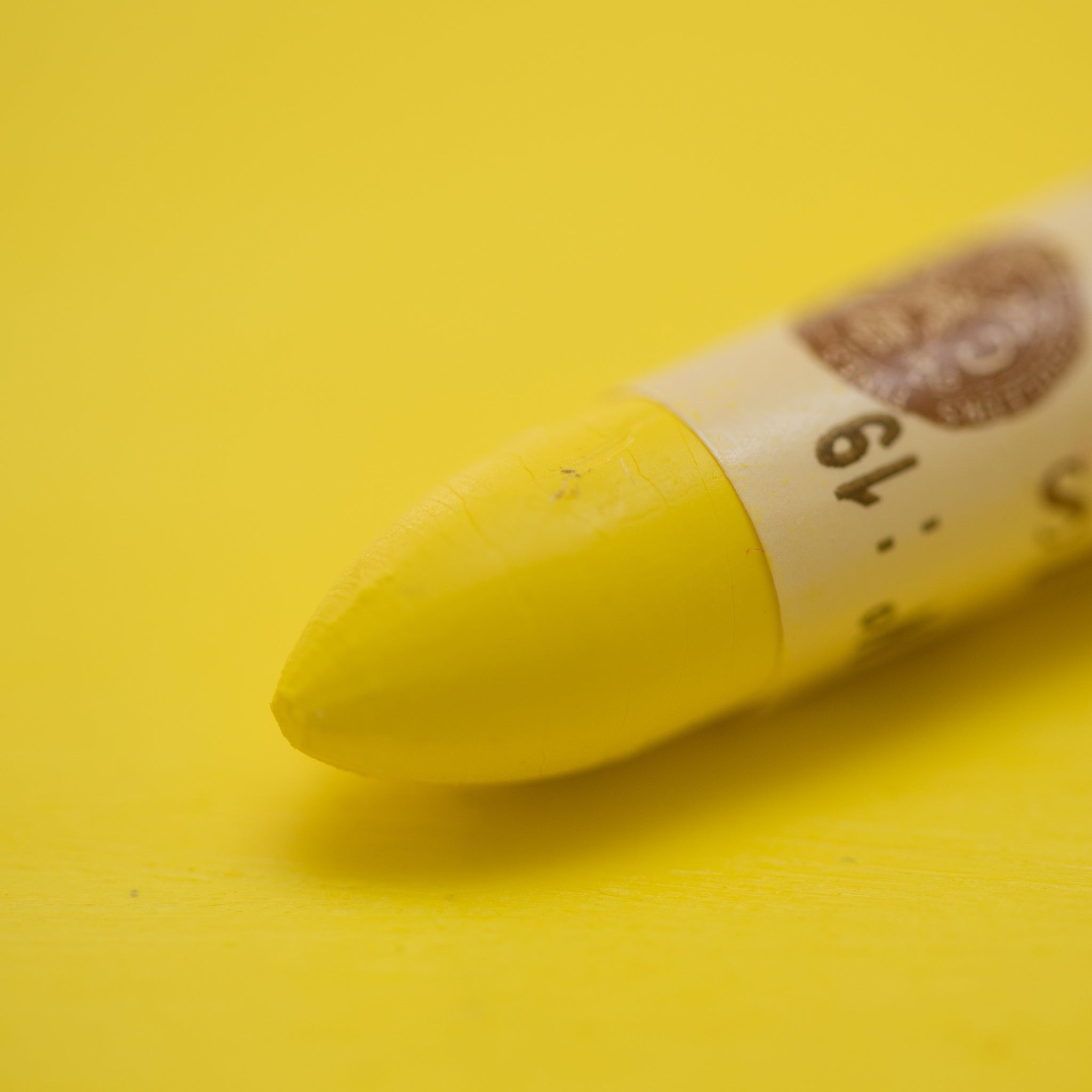 A close-up of a Sennelier oil pastel on a Yellow background