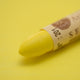 A close-up of a Sennelier oil pastel on a  yellow background.