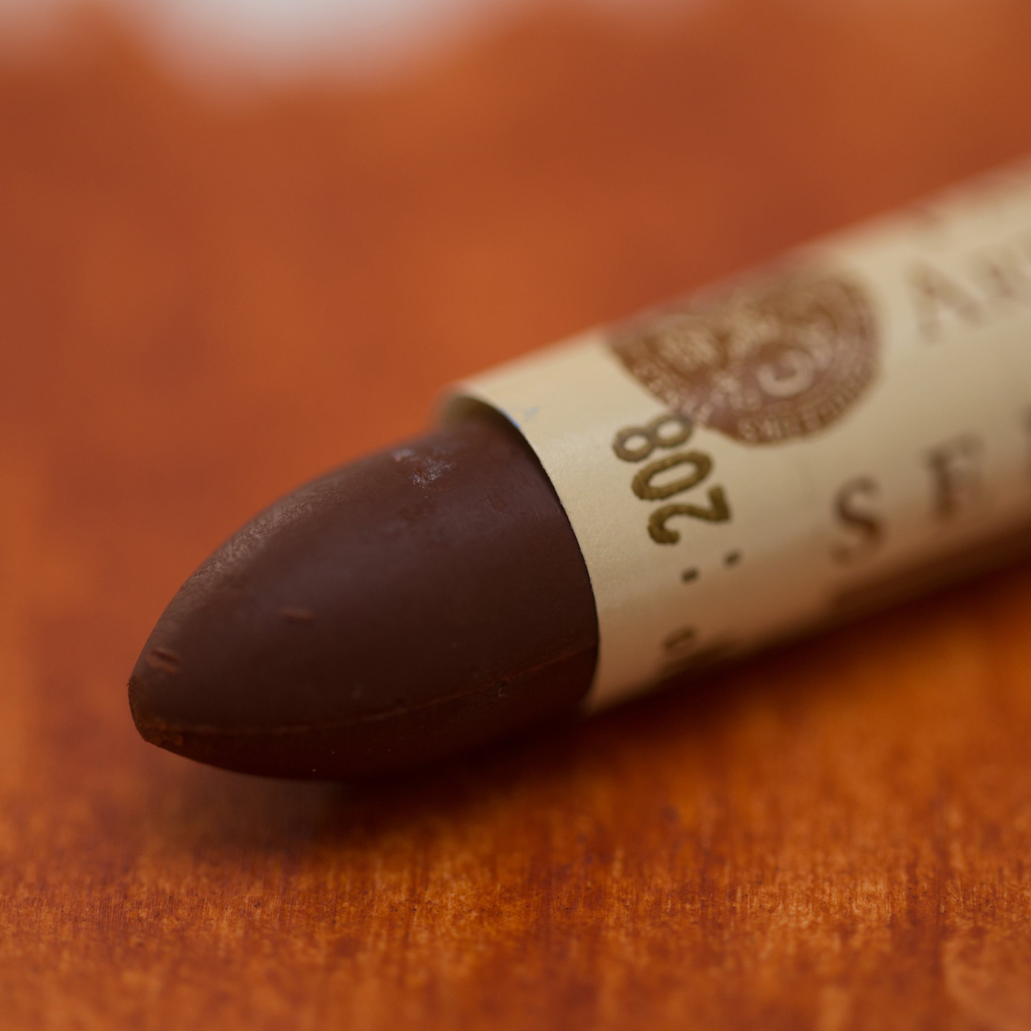 A close-up of a Sennelier oil pastel on a  brown background.