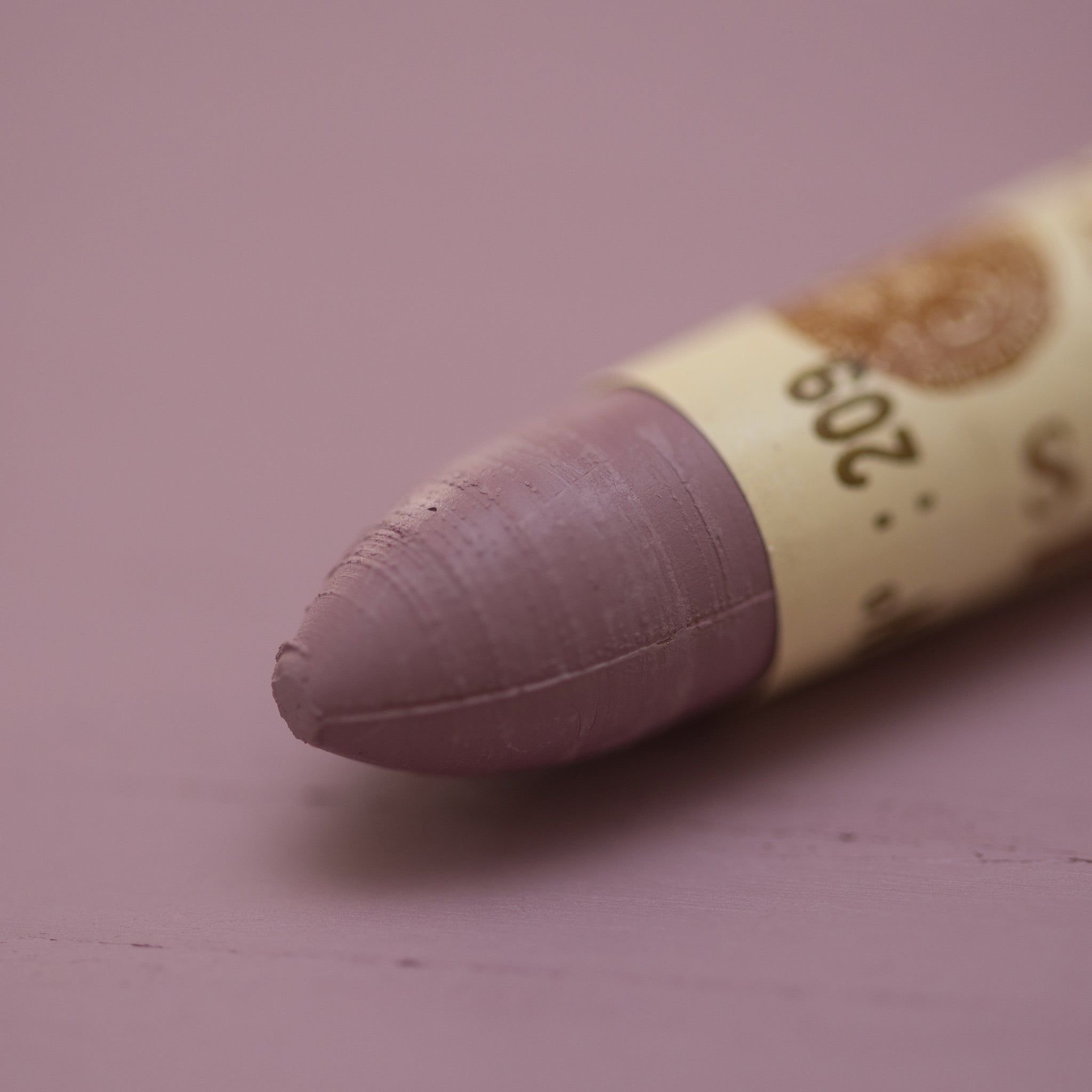 A close-up of a Sennelier oil pastel on a  violet background.