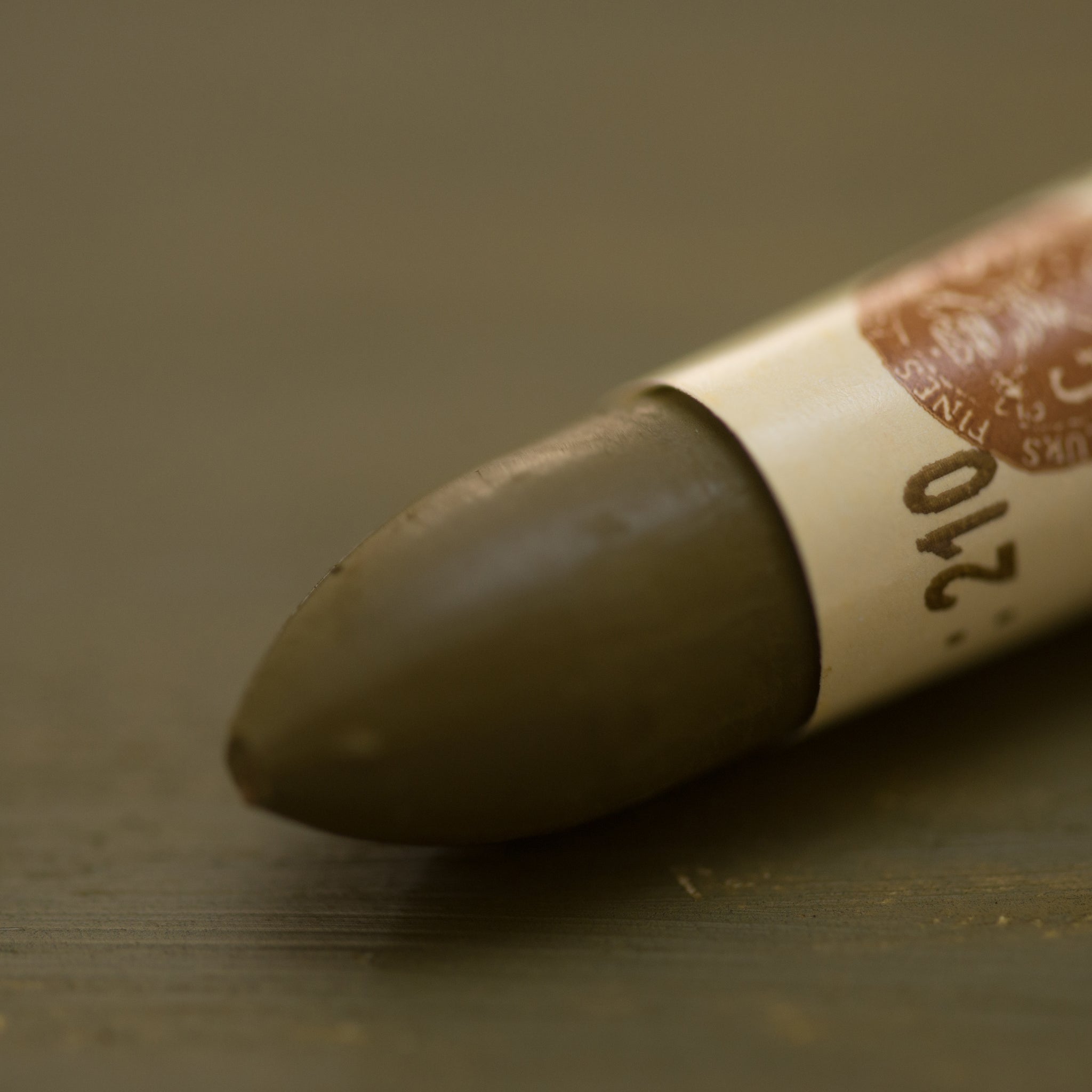 A close-up of a Sennelier oil pastel on a  brown background.