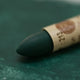 A close-up of a Sennelier oil pastel on a  green background.