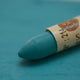 A close-up of a Sennelier oil pastel on a  green background.
