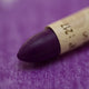 A close-up of a Sennelier oil pastel on a  purple background.