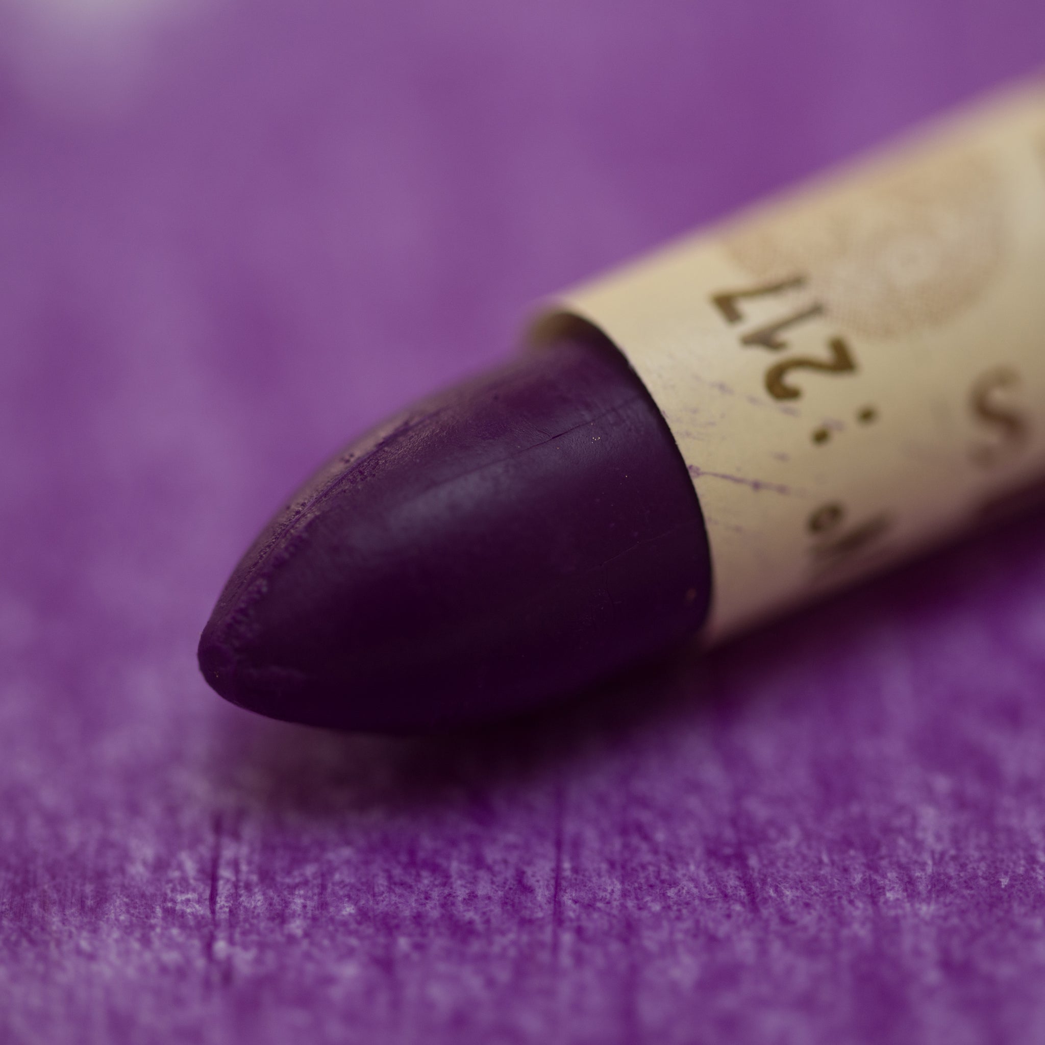 A close-up of a Sennelier oil pastel on a  purple background.