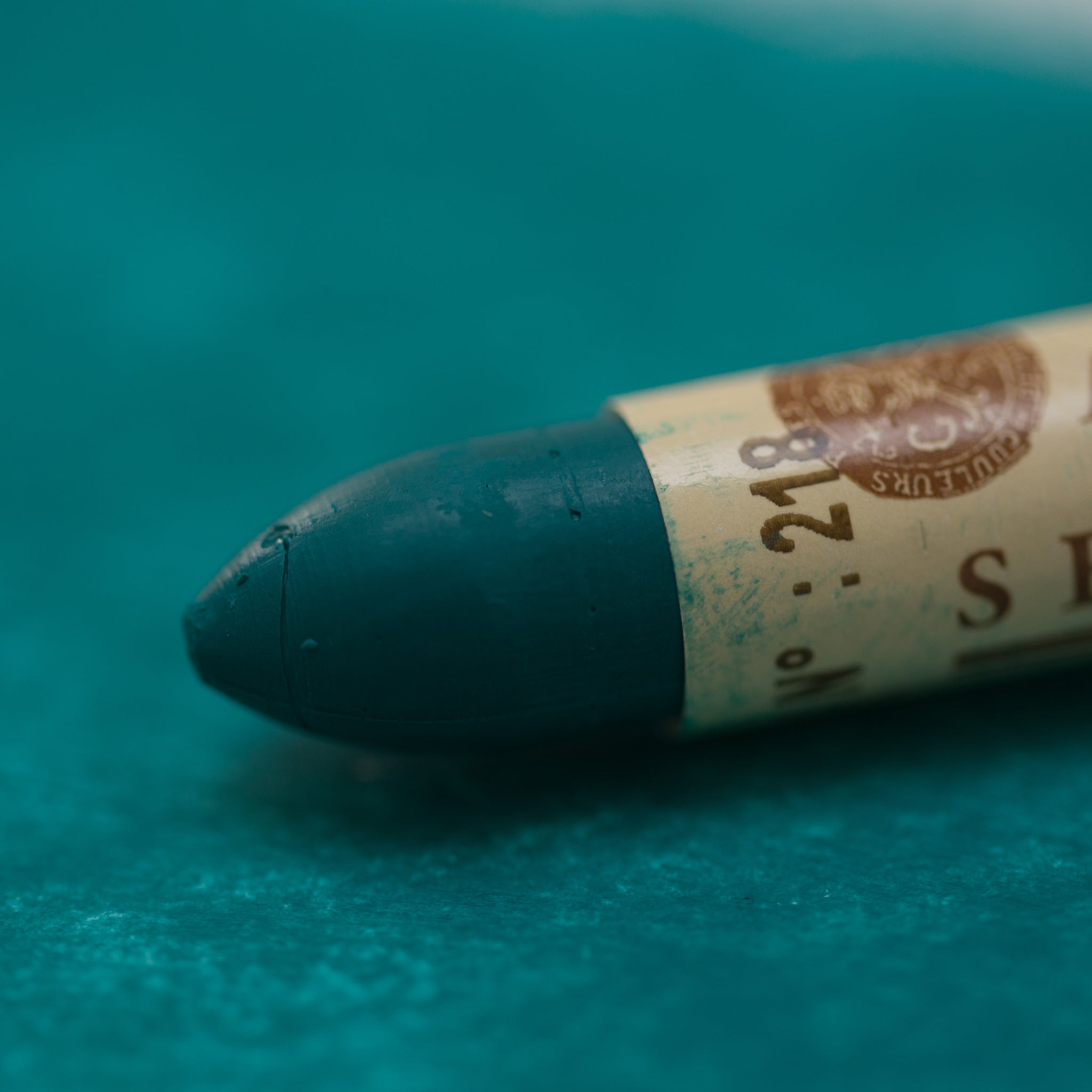 A close-up of a Sennelier oil pastel on a  green background.