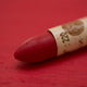A close-up of a Sennelier oil pastel on a  red background.