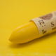 A close-up of a Sennelier oil pastel on a  yellow background.
