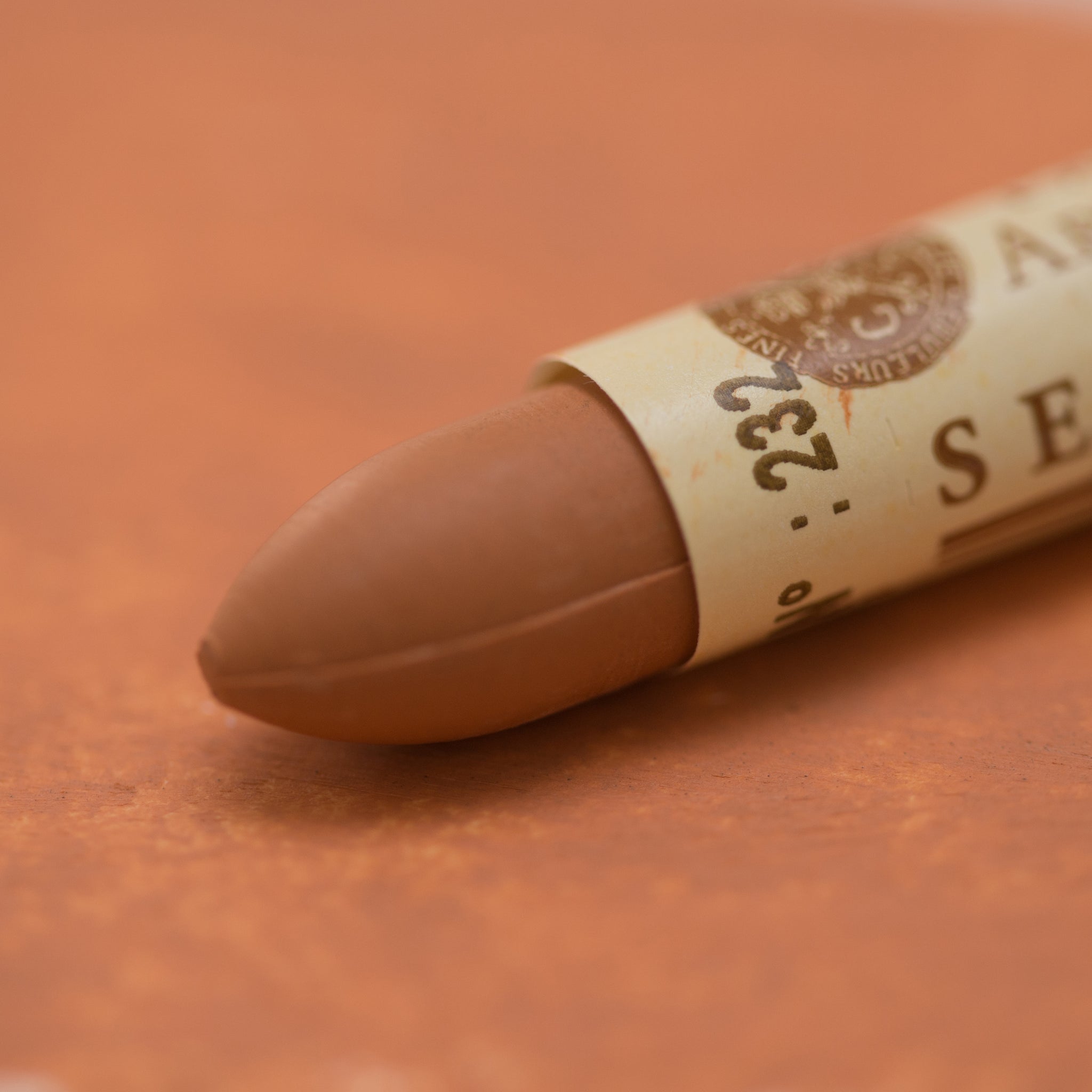 A close-up of a Sennelier oil pastel on a  brown background.