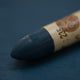 A close-up of a Sennelier oil pastel on a   dark blue background.