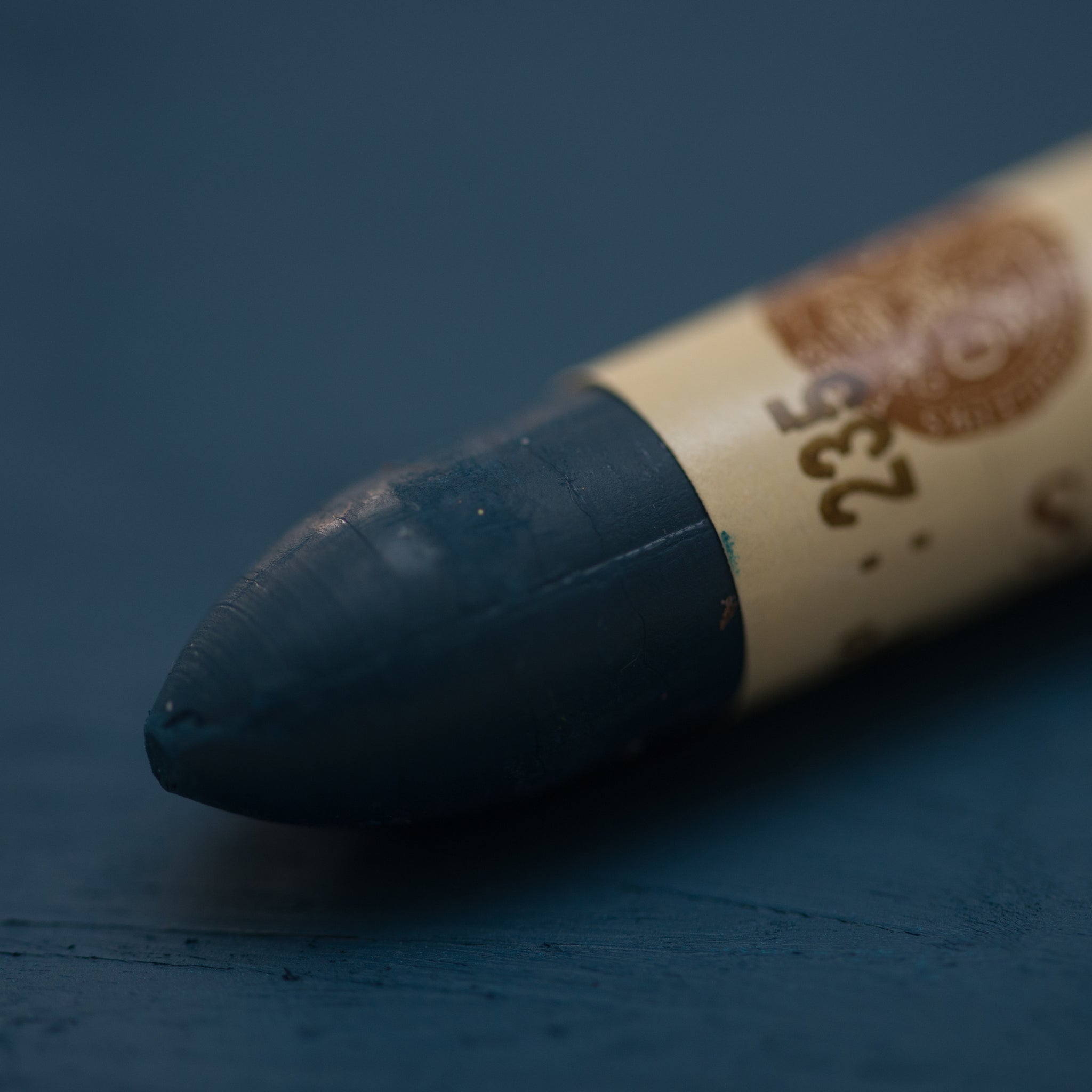 A close-up of a Sennelier oil pastel on a   dark blue background.