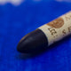 A close-up of a Sennelier oil pastel on a  blue background.