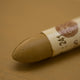A close-up of a Sennelier oil pastel on a brown background.