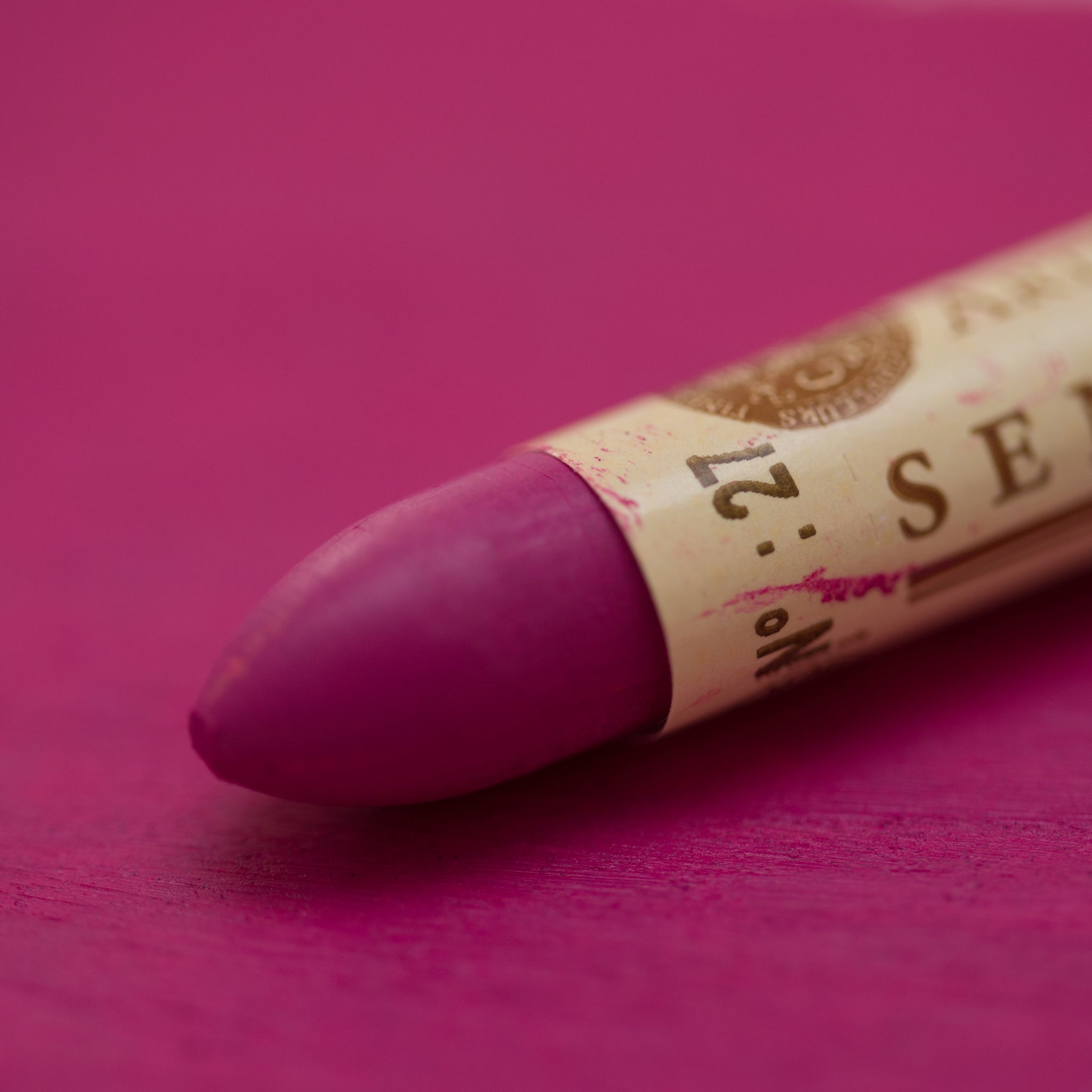   A close-up of a Sennelier oil pastel on a purple background.