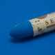 A close-up of a Sennelier oil pastel on a Blue background.