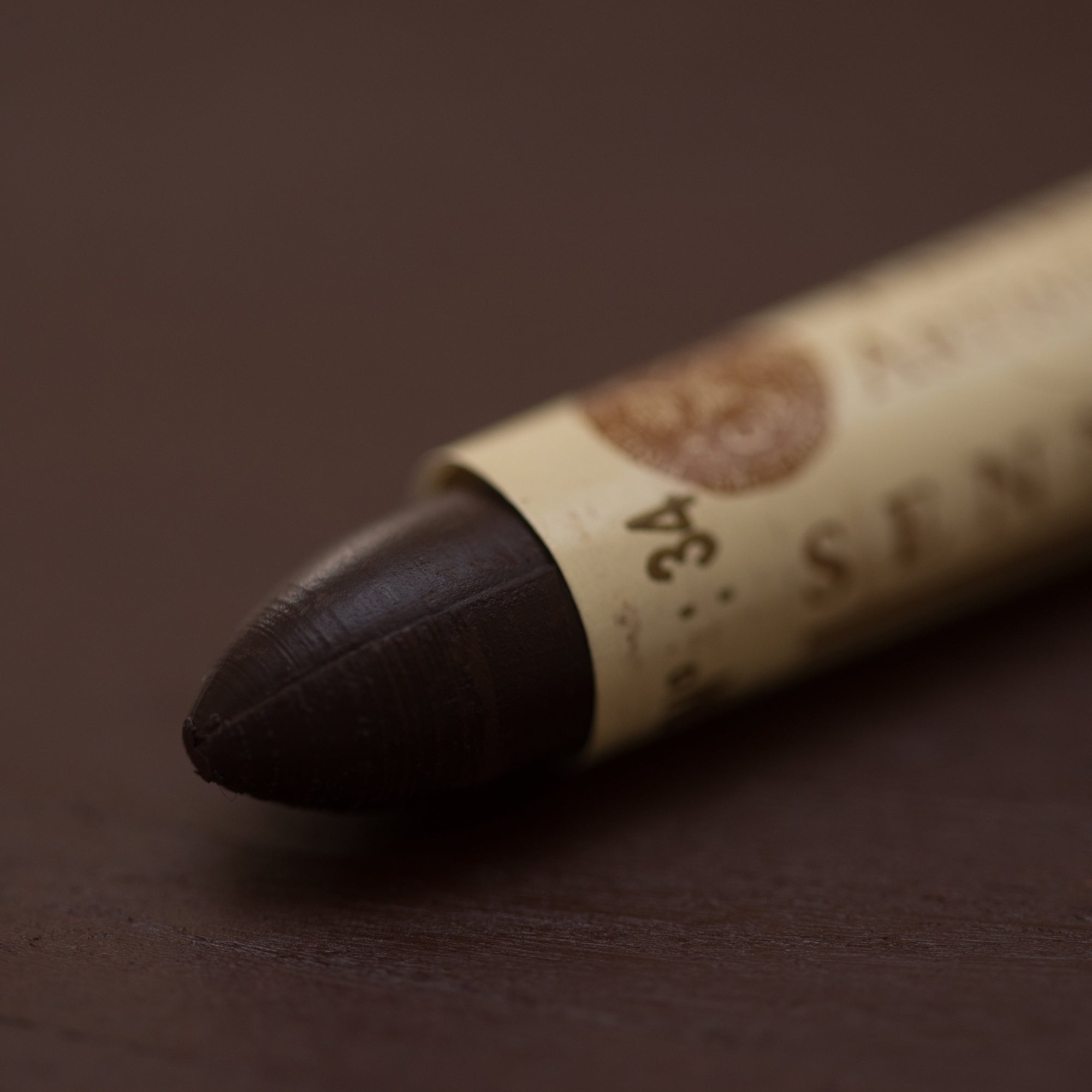 A close-up of a Sennelier oil pastel on a brown background.