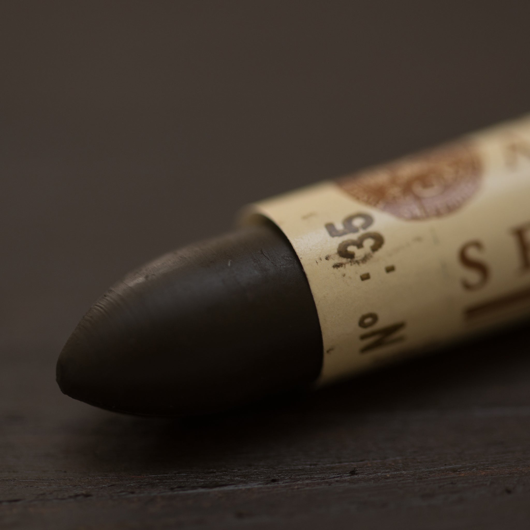A close-up of a Sennelier oil pastel on a brown background.