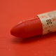 A close-up of a Sennelier oil pastel on a Red background.