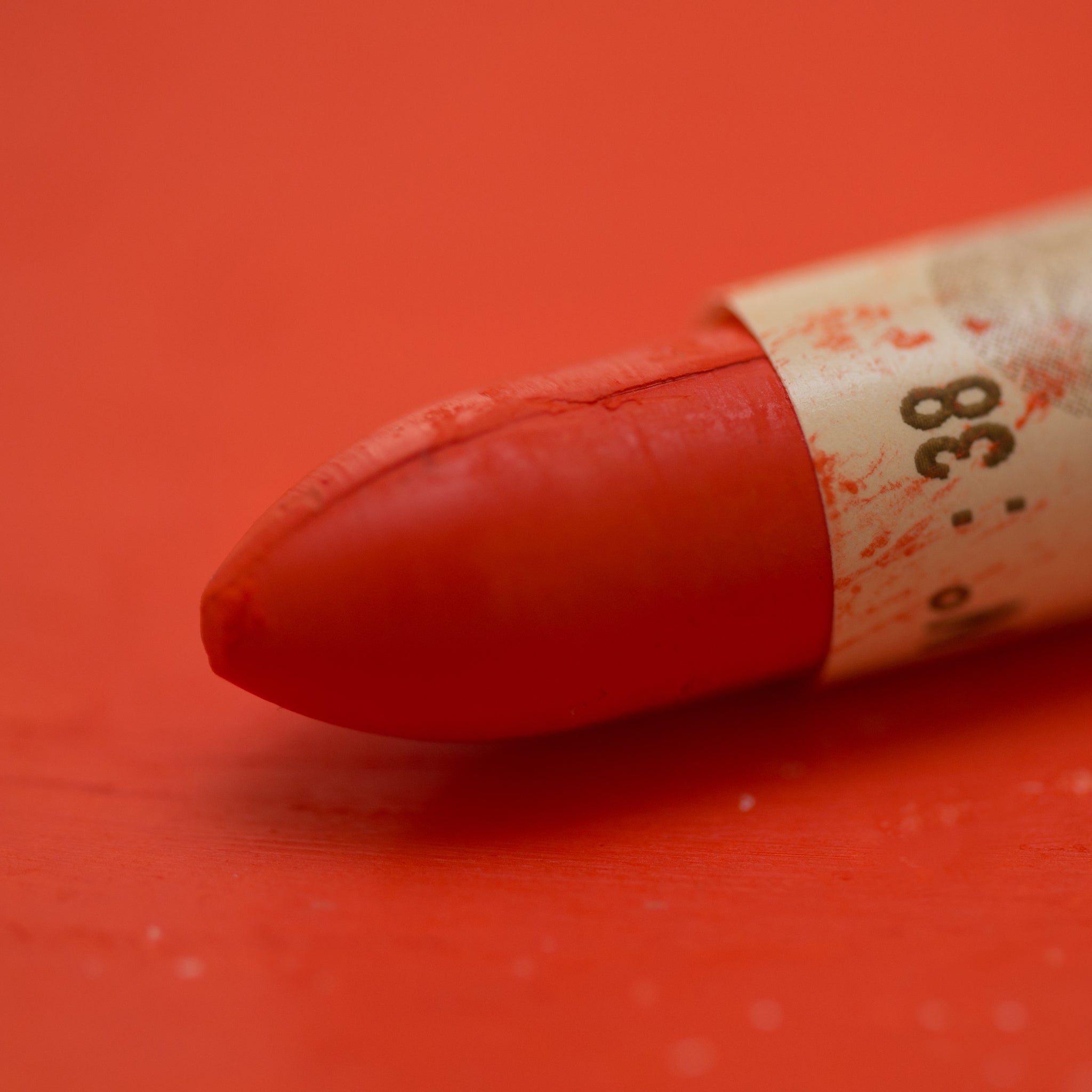 A close-up of a Sennelier oil pastel on a Red background.