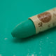 A close-up of a Sennelier oil pastel on a green background.