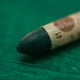 A close-up of a Sennelier oil pastel on a green background.
