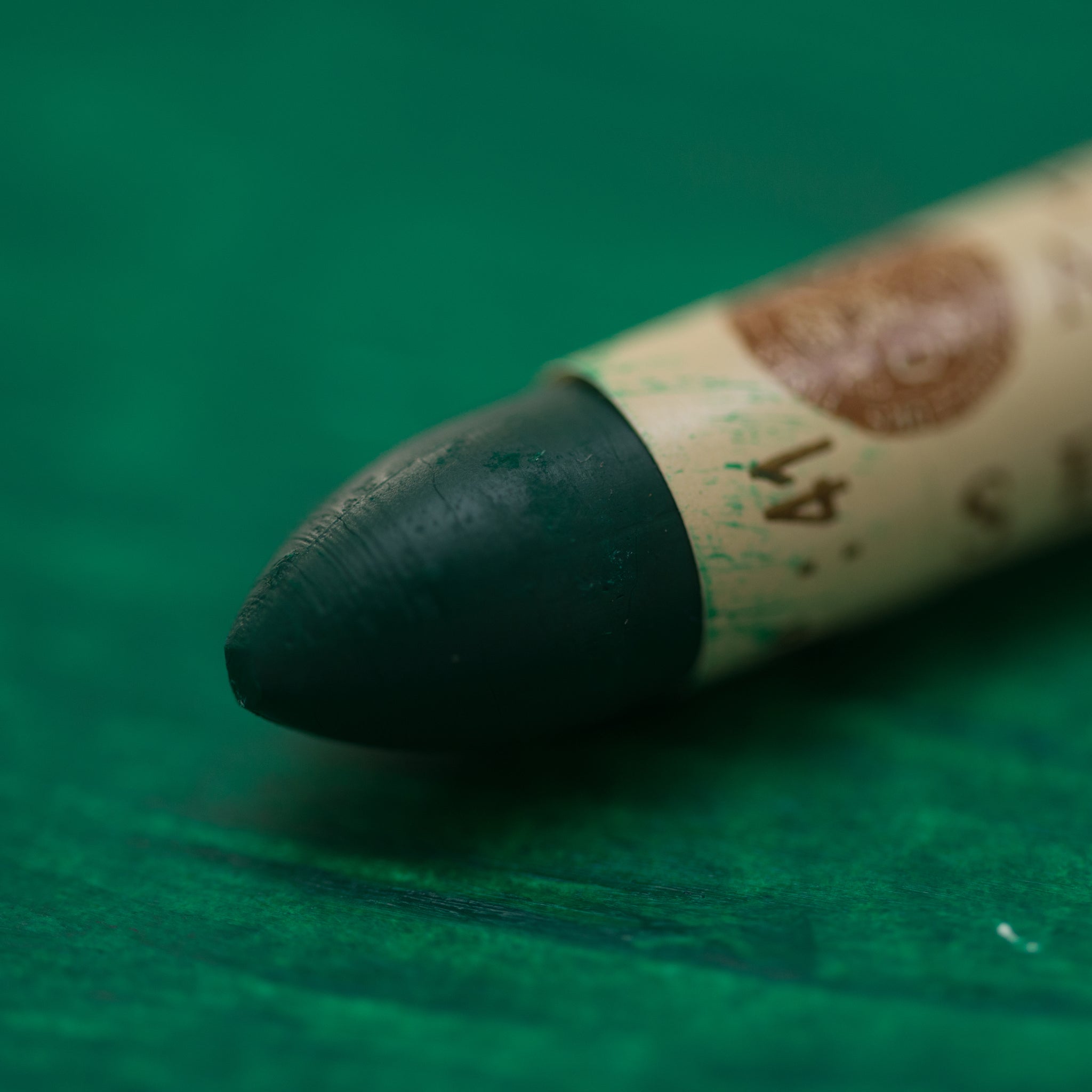A close-up of a Sennelier oil pastel on a green background.