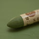 A close-up of a Sennelier oil pastel on a green background.