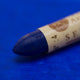 A close-up of a Sennelier oil pastel on a blue background.