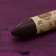 A close-up of a Sennelier oil pastel on a  dark purple background.