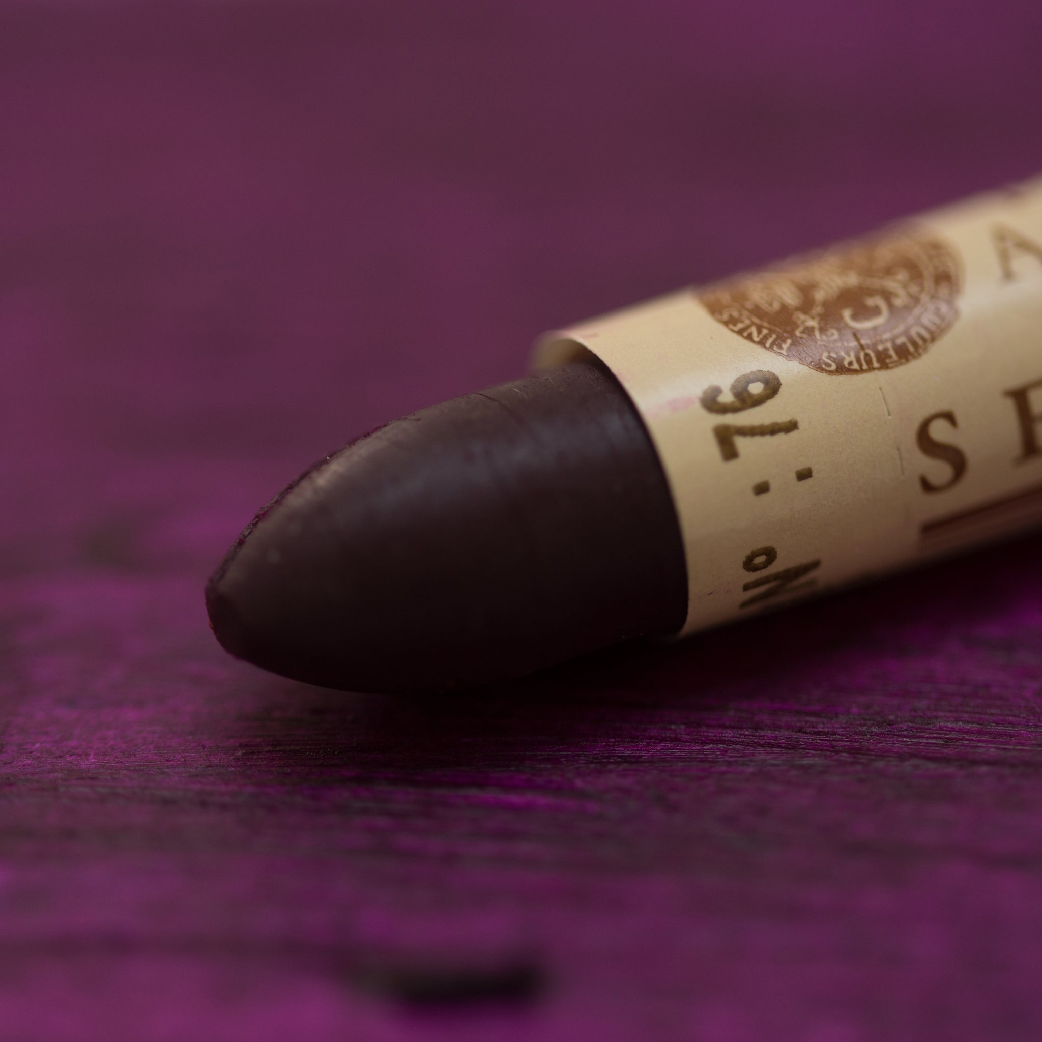 A close-up of a Sennelier oil pastel on a  dark purple background.