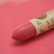 A close-up of a Sennelier oil pastel on a pink background.