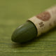 A close-up of a Sennelier oil pastel on a green background.