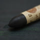 A close-up of a Sennelier oil pastel on a dark green background.