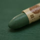 A close-up of a Sennelier oil pastel on a green background.