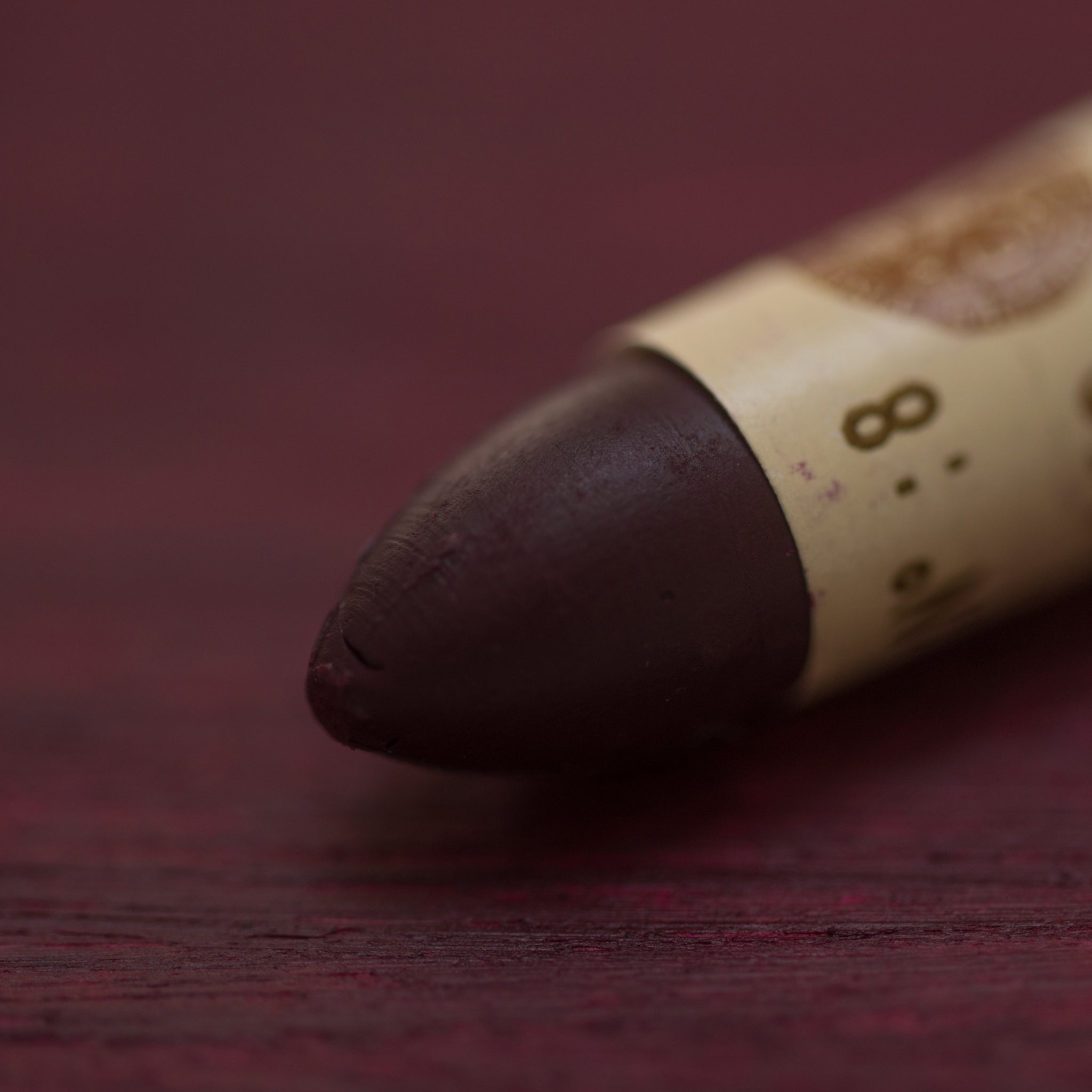 A close-up of a Sennelier oil pastel on a deep purple background.