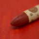 A close-up of a Sennelier oil pastel on a orange background.