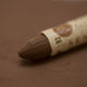 A close-up of a Sennelier oil pastel on a brown background.