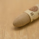 A close-up of a Sennelier oil pastel on a light beige background.