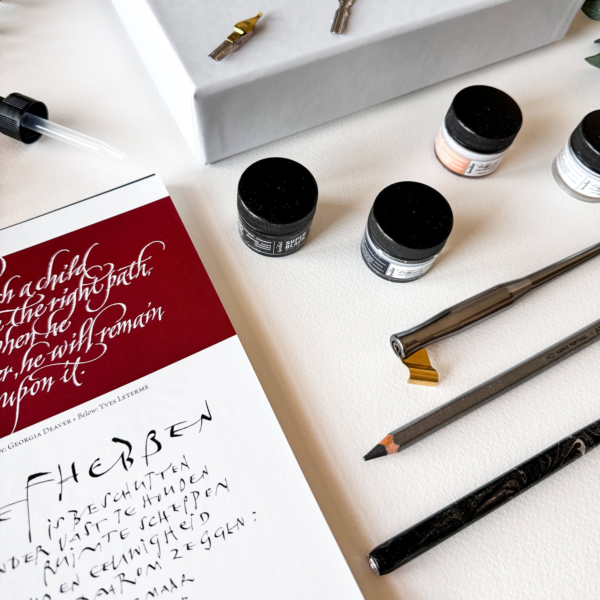 Calligraphy set with ink pots, nib holder, and a practice sheet on a white surface