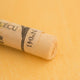 A close-up of an Orange Sennelier extra soft pastel. on the same coloured background, with the colour information printed on the paper wrap.