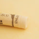 A close-up of a pale Orange Sennelier extra soft pastel. on the same coloured background, with the colour information printed on the paper wrap.