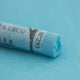  A close-up of a blue Sennelier extra soft pastel on the same coloured background, with the colour information printed on the paper wrap.