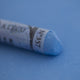  A close-up of a blue Sennelier extra soft pastel on the same coloured background, with the colour information printed on the paper wrap.