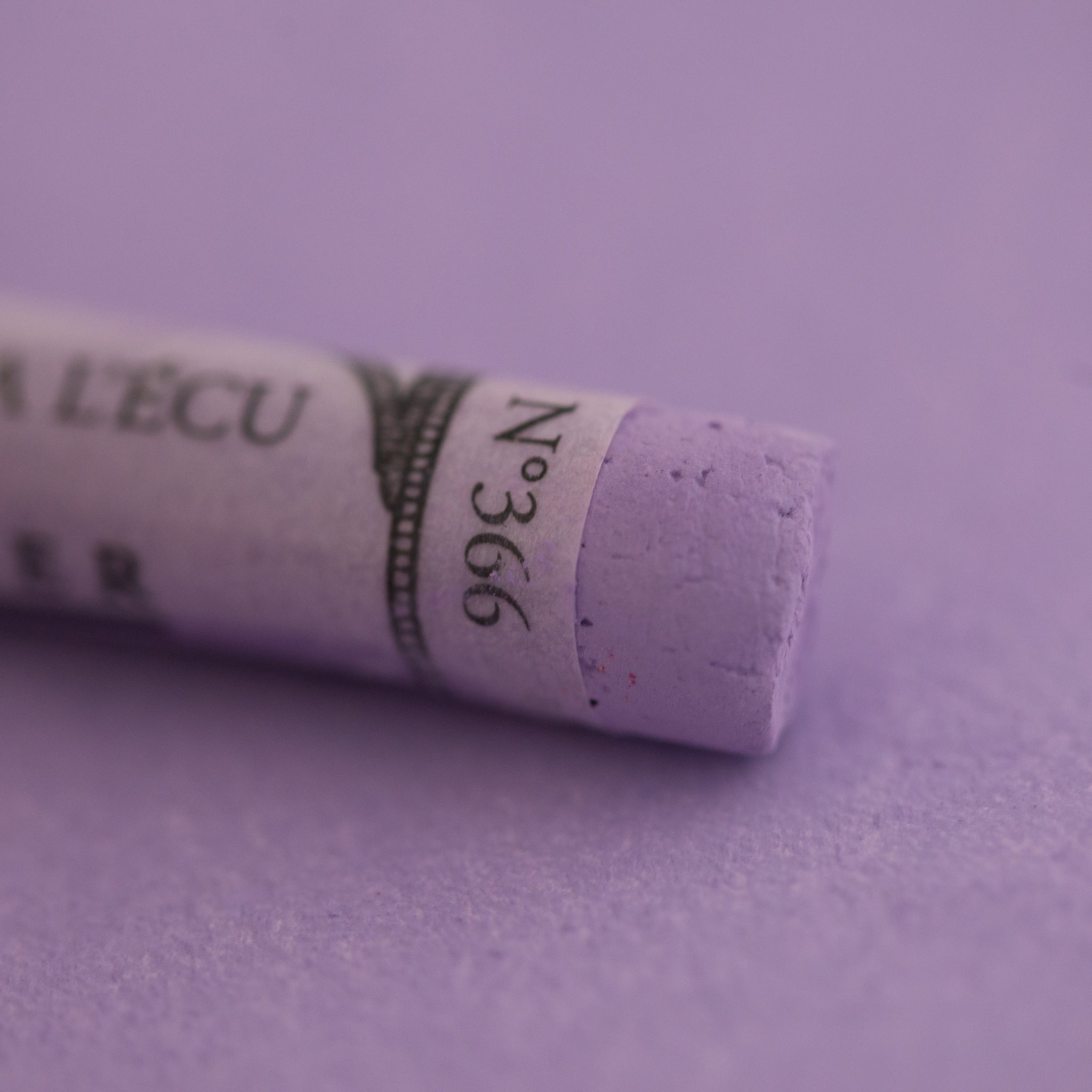  A close-up of a purple Sennelier extra soft pastel on the same coloured background, with the colour information printed on the paper wrap.