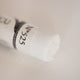 A close-up of a white Sennelier extra soft pastel. on the same coloured background, with the colour information printed on the paper wrap.