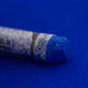  A close-up of a vibrant blue Sennelier extra soft pastel on the same coloured background, with the colour information printed on the paper wrap.